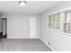 Gray carpeted bedroom features a window and white door at 1507 Fair Haven Dr, Riverdale, GA 30296