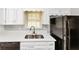 Modern kitchen with white cabinets, stainless steel sink, and black appliances at 1507 Fair Haven Dr, Riverdale, GA 30296