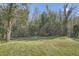 Large, grassy backyard area surrounded by a lush green forest and mature trees at 2836 Waters Sw Rd, Atlanta, GA 30354