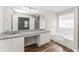 Bathroom boasts a granite countertop with dual sinks, a soaking tub, and wood flooring at 2485 Field Spring Dr, Stonecrest, GA 30058