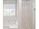 Bright bathroom featuring a white tub under a window and a shower with clear curtain at 2485 Field Spring Dr, Stonecrest, GA 30058