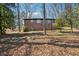Backyard with a brick house, mature trees, and fallen leaves creating a scenic, natural setting at 2696 Dodson Dr, East Point, GA 30344