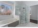 Luxurious bathroom featuring a modern tub, sleek glass-enclosed shower, and marble flooring for a spa-like experience at 7025 Bavarian Wood Pl, Buford, GA 30518