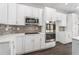 Clean kitchen view showcasing modern, stainless steel appliances against white cabinetry and dark flooring, with grey subway tile backsplash at 7025 Bavarian Wood Pl, Buford, GA 30518