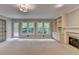 Bright living room featuring built-in shelves, a fireplace, plush carpet, and views of the surrounding greenery at 10835 Tuxford Dr, Alpharetta, GA 30022