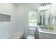 Light-filled bathroom featuring tiled walls, a modern vanity, and a bathtub for a spa-like experience at 585 Sherwood Ne Rd, Atlanta, GA 30324