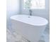 Elegant freestanding tub with a sleek faucet, paired with marble hexagonal floors and a view of a nearby window at 585 Sherwood Ne Rd, Atlanta, GA 30324