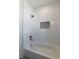 White tiled tub and shower combination featuring built in shelving at 585 Sherwood Ne Rd, Atlanta, GA 30324
