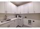 Well-lit laundry room boasts white cabinets, granite countertops, and stainless steel sink at 585 Sherwood Ne Rd, Atlanta, GA 30324