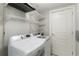 Bright laundry room with modern washer and dryer, white wire shelving, and a closed door at 700 Park Regency Ne Pl # 803, Atlanta, GA 30326