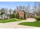 Side view of a brick home with a well-maintained lawn, mature trees, and a paved driveway at 2611 Winterthur Main Nw, Kennesaw, GA 30144