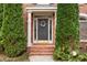 Close-up of a home's entrance with a decorated front door and manicured evergreens at 2611 Winterthur Main Nw, Kennesaw, GA 30144