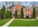 Elegant brick home with manicured lawn, tall evergreens, and a welcoming front entrance at 2611 Winterthur Main Nw, Kennesaw, GA 30144
