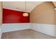 Dining room featuring a pendant light, red accent wall, wainscoting, and neutral carpet at 4531 Flowering Br, Powder Springs, GA 30127