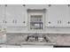 Kitchen sink under a window, featuring white cabinets, granite countertops, and a tiled backsplash at 9258 Westview Sw Dr, Covington, GA 30014