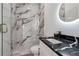 Modern bathroom features marble walls and countertops, glass shower and a backlit mirror at 2312 Herring Sw Rd, Atlanta, GA 30311