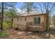 Back of house featuring wood siding, small deck, and brick chimney in wooded yard at 4564 Cypress Ridge Ct, Stone Mountain, GA 30083
