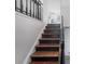 View of the wooden staircase with black railings leading up to a bright, open area at 3274 Adelade Ct, Lithonia, GA 30038