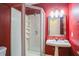 Bright bathroom with a corner shower, pedestal sink, and vibrant red walls at 2914 Lenox Ne Rd # 12, Atlanta, GA 30324