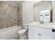 Well-lit bathroom with a combination shower and tub, neutral gray tile, and white vanity at 3836 Alice Ln, Suwanee, GA 30024