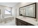 Bright main bathroom boasts marble floors, a double vanity, soaking tub, and large mirror over the sink at 3836 Alice Ln, Suwanee, GA 30024