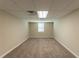 This carpeted basement features neutral paint, a drop ceiling, and a bright window at 1059 Buckboard Ct, Douglasville, GA 30134