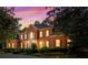 Stately brick home exterior with red shutters, professional landscaping, and driveway at dusk at 440 Dix Lee On Dr., Fayetteville, GA 30215