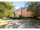 Stately brick home featuring a circular driveway, manicured landscaping, and bright red shutters at 440 Dix Lee On Dr., Fayetteville, GA 30215