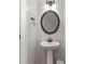 A convenient half bathroom featuring a pedestal sink, round mirror, and neutral wall color at 1570 Lenox Overlook Ne Rd, Atlanta, GA 30329