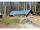 Chicken coop with tin roof sits on a gravel and grass-filled lot surrounded by trees and fence, enhancing country charm at 158 Lambeth Dr, Hiram, GA 30141