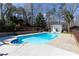 An inviting in-ground swimming pool surrounded by a concrete deck, a wooden fence, and mature trees provides a peaceful outdoor retreat at 158 Lambeth Dr, Hiram, GA 30141