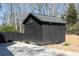 Dark storage shed for pool, constructed with durable wood, sits on a concrete slab amidst gravel and trees at 158 Lambeth Dr, Hiram, GA 30141