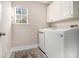 Laundry room featuring white cabinets, a front-load washer and dryer, and a window with natural light at 2275 Holly Run Dr, Jonesboro, GA 30236