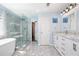 Bright bathroom featuring a soaking tub, frameless shower, double sink vanity with marble countertop, and a tiled floor at 3876 Toccoa Falls Dr, Duluth, GA 30097