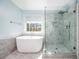 Bright bathroom showcasing a soaking tub, frameless shower, and a large window that provide ample natural light at 3876 Toccoa Falls Dr, Duluth, GA 30097