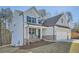 Side view of a gray two-story home with stone accents, three car garage, a porch with rocking chairs, and landscaped yard at 115 Laurelwood Ln, Dallas, GA 30157