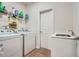 Well-equipped laundry room with washer, dryer, sink, and storage shelf for cleaning supplies at 115 Laurelwood Ln, Dallas, GA 30157