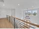 Upstairs hallway with wood floors and metal railings overlooking the entry featuring a modern light fixture at 195 Hope Hollow Rd, Loganville, GA 30052