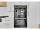 Modern kitchen with built-in double ovens and sleek white cabinetry at 195 Hope Hollow Rd, Loganville, GA 30052