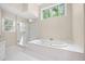 Bright bathroom featuring a soaking tub, glass shower, and large window with serene outdoor views at 535 Woodbrook Way, Lawrenceville, GA 30043