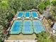 Aerial view of multiple tennis courts in a neighborhood with meticulously maintained landscaping and pristine blue courts at 535 Woodbrook Way, Lawrenceville, GA 30043
