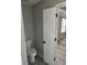 Small, private water closet with a white toilet, gray walls, and views into a separate living space at 4080 Brushymill Ct, Loganville, GA 30052