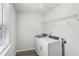 Practical laundry room equipped with modern washer and dryer units and a wire shelf at 6910 Winchester Pl, Fairburn, GA 30213