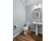 This half-bathroom features a pedestal sink, a decorative mirror, and wood-look flooring at 2360 Brookgreen Commons, Kennesaw, GA 30144