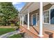 Inviting covered front porch featuring white columns, a blue front door, and beautiful windows at 5635 Charleston Bay Dr, Cumming, GA 30041