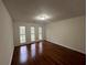 Bedroom features gleaming hardwood floors, neutral paint, and three windows with outside views at 257 Forest Lake Rd, Lawrenceville, GA 30046