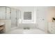 All-white bathroom featuring a glass-enclosed shower and a tub with a glass block window at 4236 Providence Ln, Tucker, GA 30084