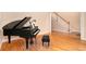 Elegant living room with hardwood floors and a grand piano beside the staircase at 4236 Providence Ln, Tucker, GA 30084