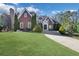 Exterior shot of elegant brick home with manicured lawn, garden, and circular driveway at 821 Camden Park Ct, Atlanta, GA 30342