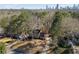 Aerial shot of a suburban home surrounded by mature trees with city skyline in the distance at 725 Glengary Ne Way, Atlanta, GA 30342